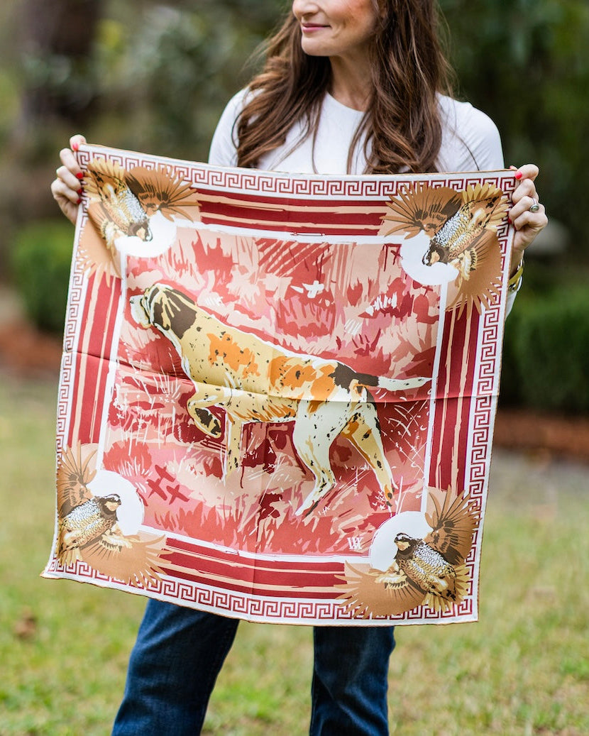 woman holding a wine colored silk scarf with a bird dog and quail design