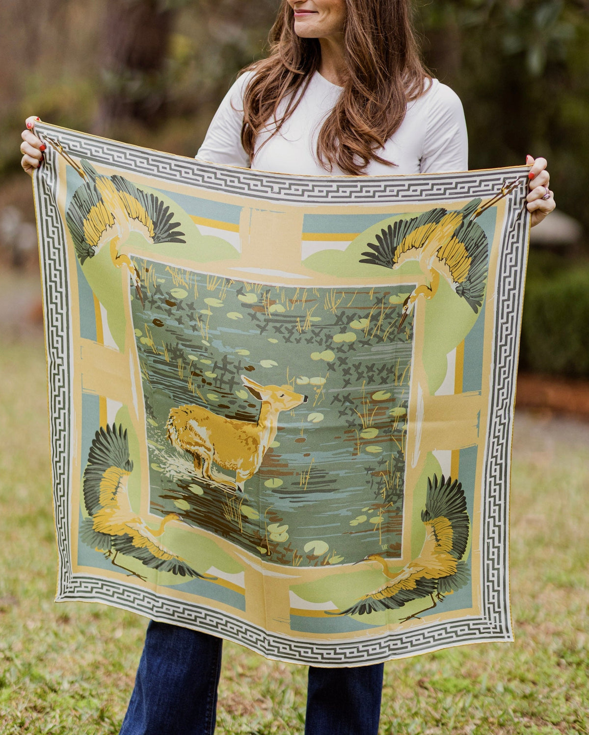 Person holding a silk scarf with scenic deer design outdoors