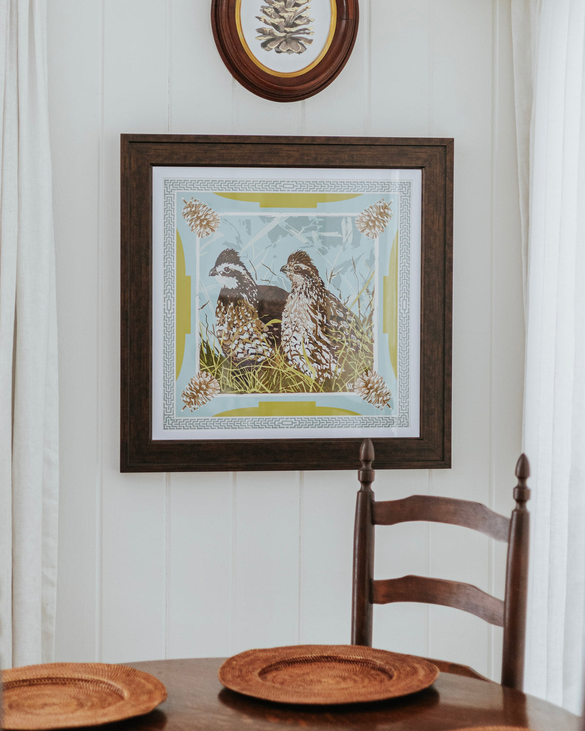 framed print of a pair of bobwhite quail in a green and blue with pine cones in the corner. 