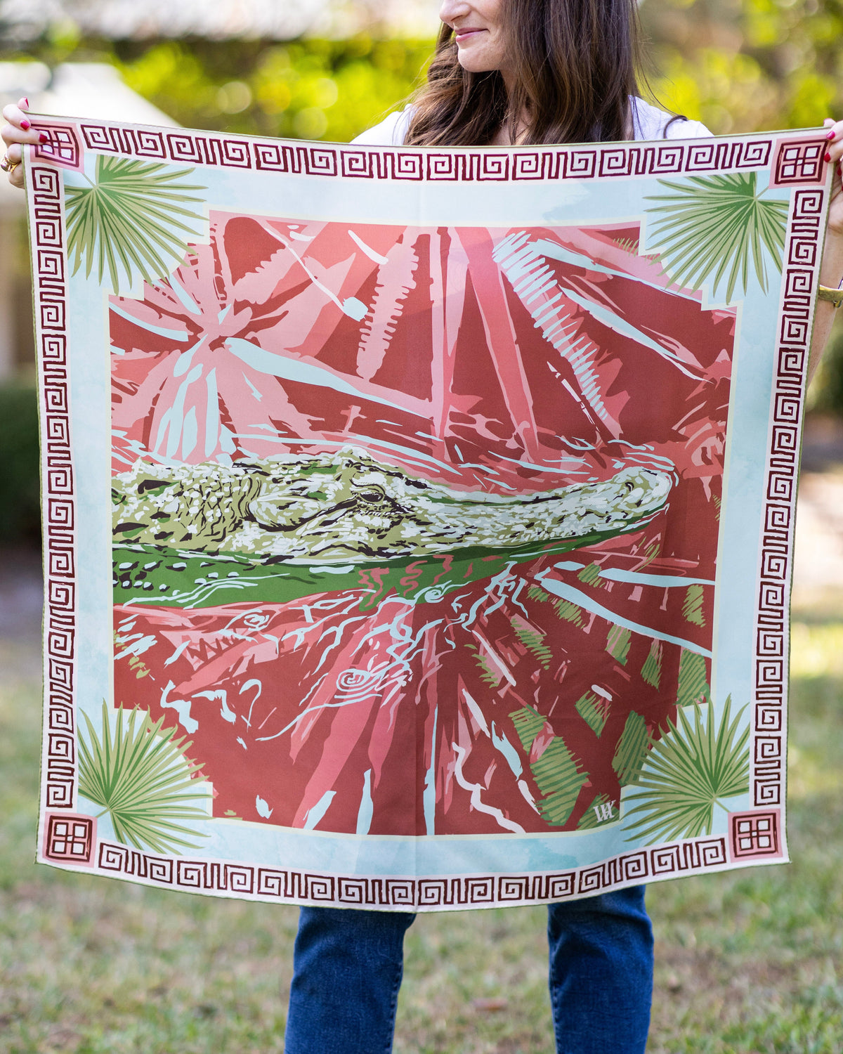 Person holding a decorative towel with a pink and green design outdoors