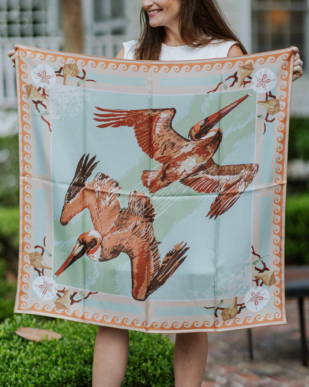 Person holding a square scarf with pelican design outdoors