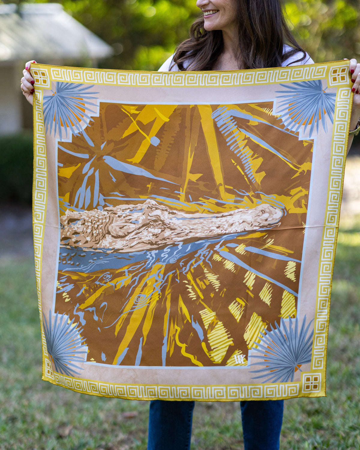 Person holding a decorative fabric with nature-themed alligator and palmetto design 