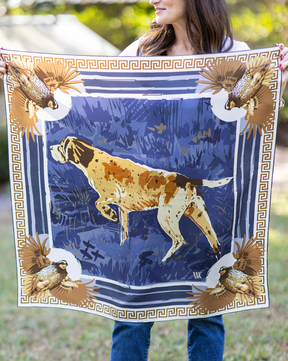 Person holding a large scarf with a hunting scene design featuring a dog and birds.
